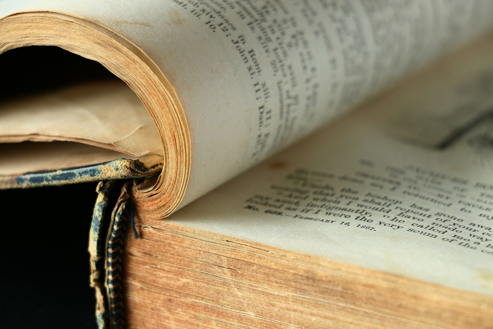 Two old books lying open one on top of the other, showing the worn edges of their pages